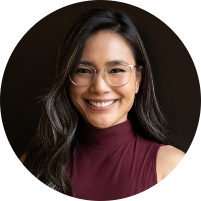 Smiling woman with glasses and purple sleeveless shirt.