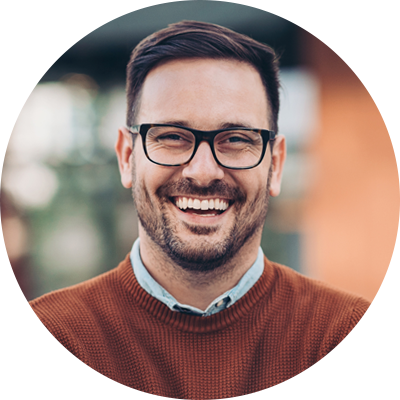 Smiling testimonial man with glasses and dark orange sweater.