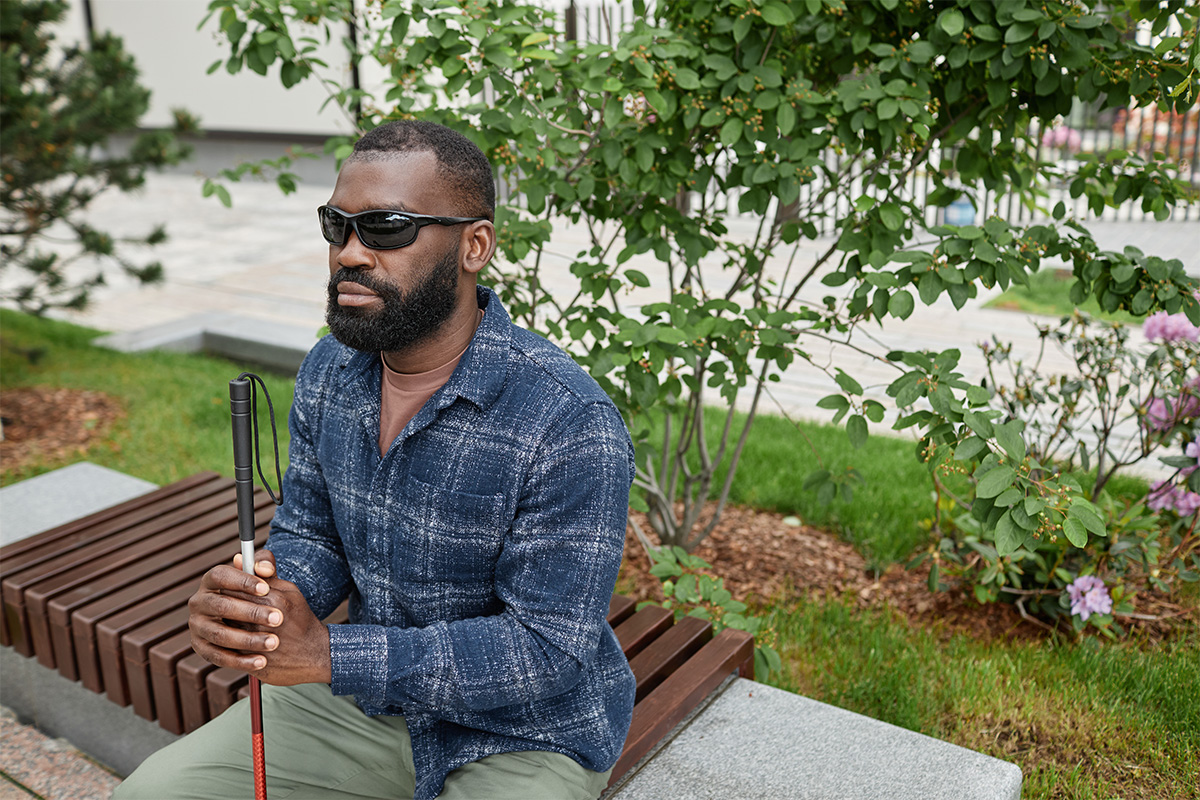 A blind man relaxes at the park as he thinks about emergency planning