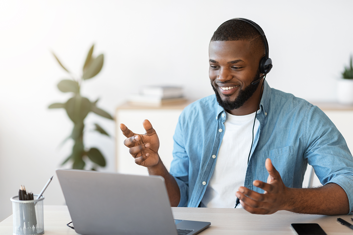 A happy Ad Astra interpreter smiles at his laptop while working with a client. 