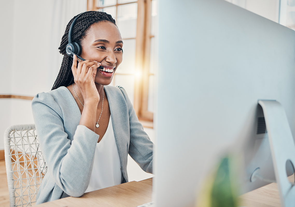 A woman wearing a headset sits at a desk with a computer. She is speaking into the headset during a meeting discussing how mistranslations impact insurance